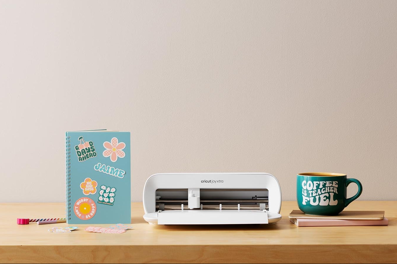 Cricut Joy Xtra Machine with printable stickers made for a notebook and a teacher mug made with vinyl